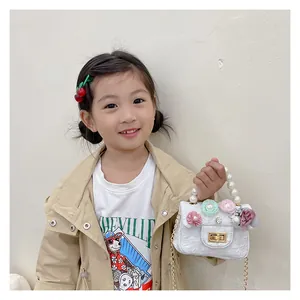 Detail of white girls mini bag with floral appliques, pearl handle and gold chain strap