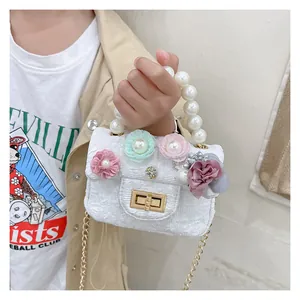 Detail of girls mini tweed bag featuring 3D floral accents and white pearl handle