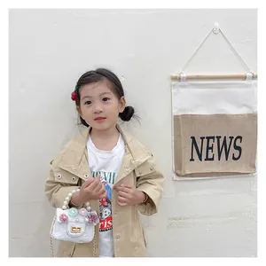 Girl wearing a khaki trench coat holding a white lace flower purse with pearl chain