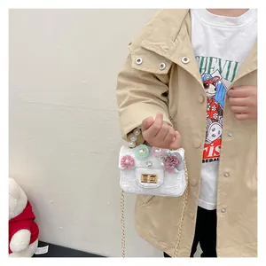 Detail of girls tweed mini bag with pearl handle and 3D floral accents with gold chain