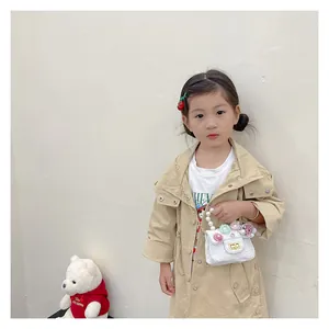 Detail view of kids' white floral bag with pearl handle and golden chain on a mini coat