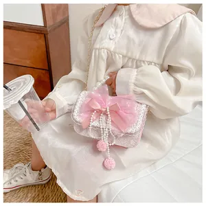 Detail of pink children's bag featuring pearl handle, lace trim and a large mesh bow