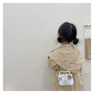 Detail of white textured mini bag with 3D floral accents and pearl handle for girls