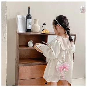 Pink lace girls' crossbody bag with oversized bow and pearl handle detail