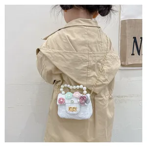 Detailed back view of a child model wearing a white tweed mini bag with pearl handle