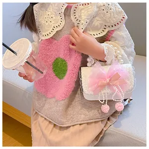 Detail of pink bow and pearl handle on a white lace crossbody bag for girls