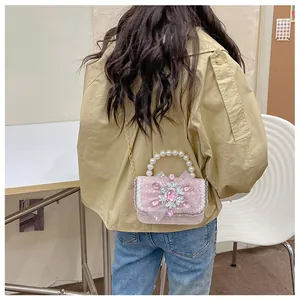 Pink lace crossbody bag with pearl handle and bow shown worn on child's shoulder