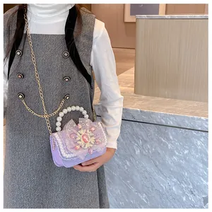 Close-up of girls purple crossbody bag with lace bow, pearl handle, and rhinestone snowflake