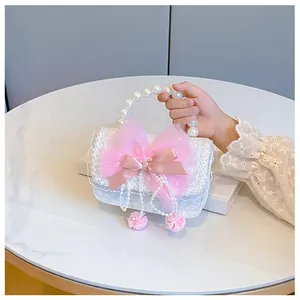 Detail of child handbag with pink tulle bow, pearl handle and woven texture detail