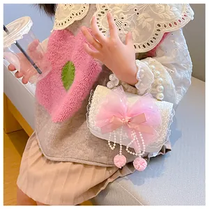 Detail of white lace kids handbag with pink mesh bow and elegant pearl handle straps