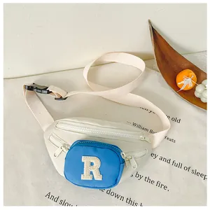 Detailed view of kids' crossbody bag with blue R embroidery on premium cream canvas