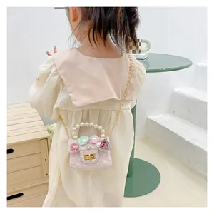 Detail of pink lace girls' bag featuring floral accents and a white pearl handle strap