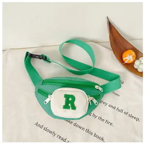 Detail of kids chest bag with green 'R' letter patch and adjustable buckle strap