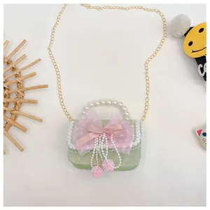 Detail of green kids handbag with pink mesh bow, lace edges and pearl bead handle