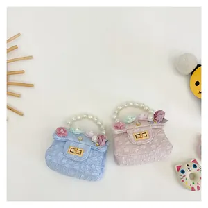 Close-up of girls' mini handbags with pearl handles and 3D floral accents with gold twist locks
