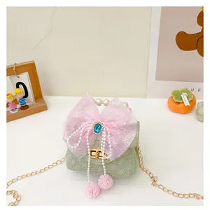 Detail der grünen geprägten Kindertasche mit rosa Schleife, Perlengriff und Pompons