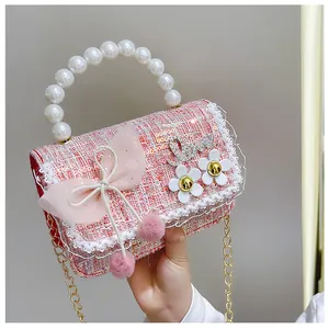 Detail of pink tweed girl handbag with pearl handle, tulle bow, and daisy decor