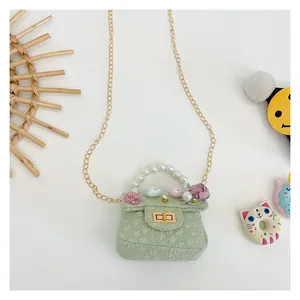 Detail view of light green girls' mini purse with floral accents and pearl handle