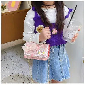 Detail of pink woven crossbody bag with pearl handle and bow for young girls