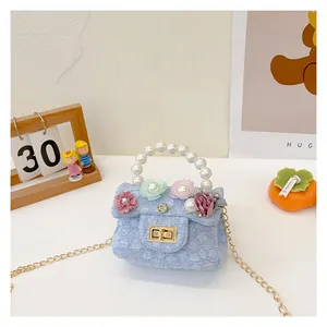 Detail of light blue floral kids mini bag with pearl handle and golden twist lock