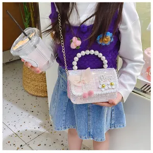 Close-up of kids sequin shoulder bag with pearl handle, pink bow and floral accents