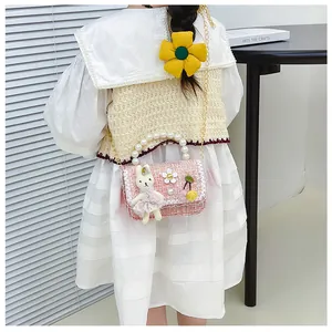 Rear view of a girl wearing a pink tweed crossbody bag with pearl handle and rabbit toy