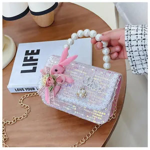 Detail of pink sequin tweed crossbody bag with pearl handle and plush bunny doll charm