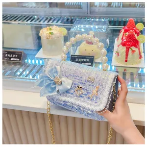 Close-up of blue tweed children handbag with pearl handle and rhinestone details