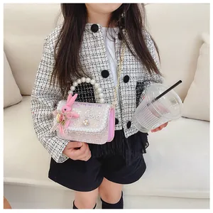 Detail of tweed girl's handbag with pearl handle, lace trim, and plush bunny charm