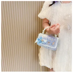 Close-up of light blue tweed kids handbag with pearl handle and bow decoration