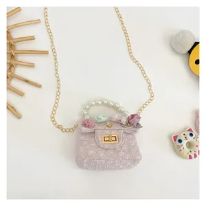Detail of pink fabric girl's bag with floral decor, pearl handle, and gold chain