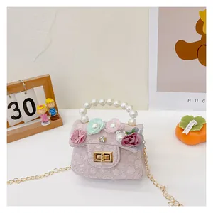 Detail of pink lace fabric with colorful floral accents and pearl handle on mini kids purse