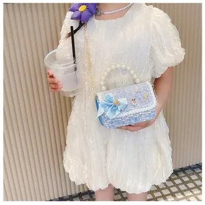 Girl's blue tweed crossbody bag with pearl handle and bow detail shown on a model