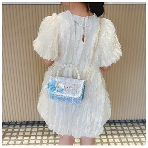 Detail of child wearing blue tweed bag with pearl handle and ribbon bow