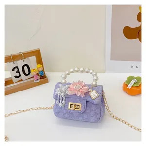 Close-up of purple tweed girls' bag with pearl handle, floral decor and gold lock
