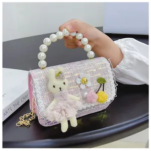 Close-up of girls' tweed handbag featuring pearl handle, plush bunny, and lace trim