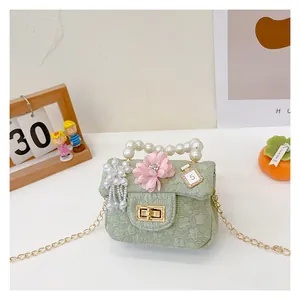 Detail of light green quilted mini bag featuring pearl handle and flower charm ornaments