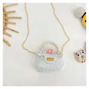Detail of white quilted girl's crossbody bag with pearl handle and flower charm