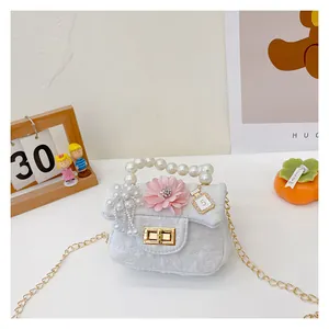 Detail of white mini bag with pearl handle, pink flower, and gold chain for girls