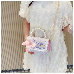 Pink tweed kids bag with pearl handle and bow, shown on model with white dress