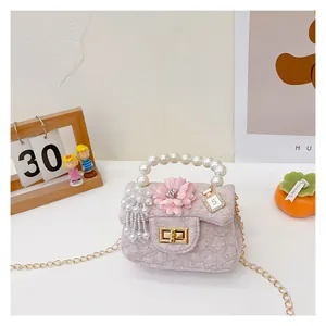 Detail of pink floral mini bag with pearl handle, gold chain, and crystal perfume charm