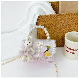 Close-up of pink tweed girl's handbag with pearl handle and plush rabbit doll detail