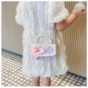 Girl wearing pink tweed crossbody bag with pearl handle and satin bow detail