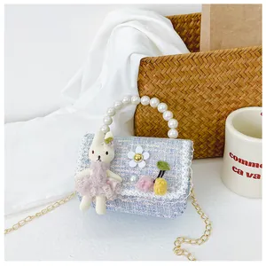 Detail of blue tweed girl bag with pearl handle, rabbit charm and lace trim finish