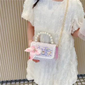 Kids tweed handbag with pearls and bow decoration shown on a white dress model