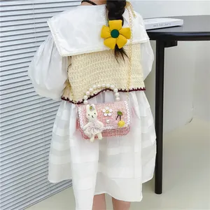 Pink tweed crossbody kids bag with pearl handle and plush bunny detail on a model
