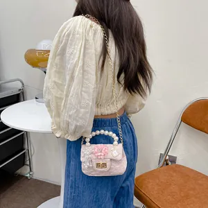 Pink tweed mini bag for girls with pearl handle and floral charms shown on model