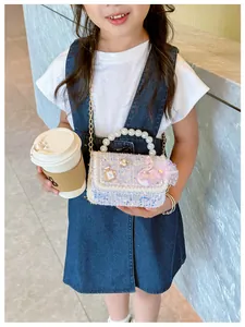 Detail of girls' sequin handbag with pearl handle, swan patch, and gold chain strap