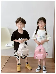 Détail de mini sacs à dos crème et roses avec logos de marque portés par enfants