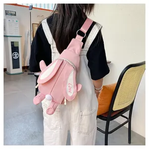 Close-up of pink rabbit crossbody bag with long ears and plush ball detail on kid model